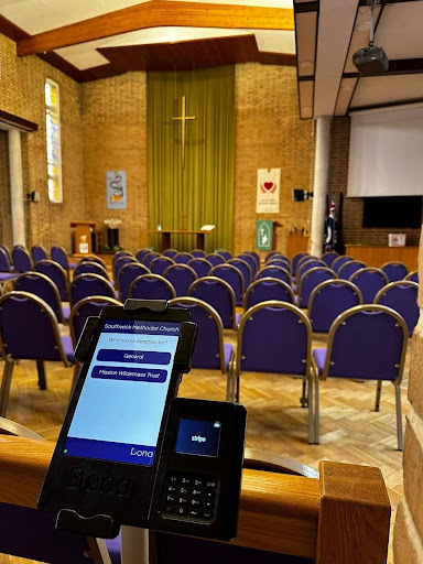 Dona donation terminal in a church with lots of chairs