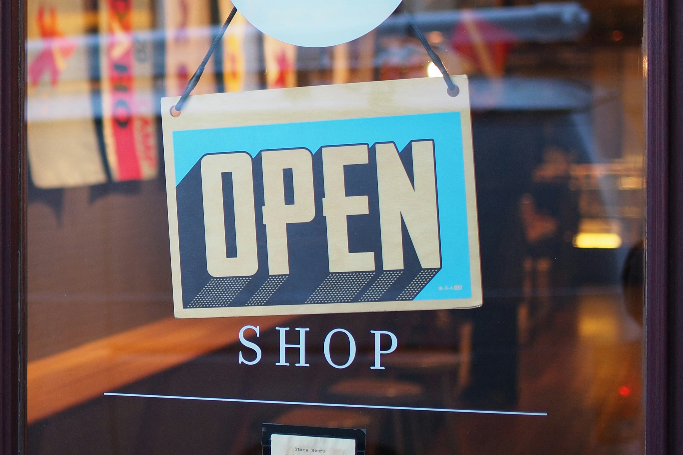 Blue open shop sign on the window of a charity shop